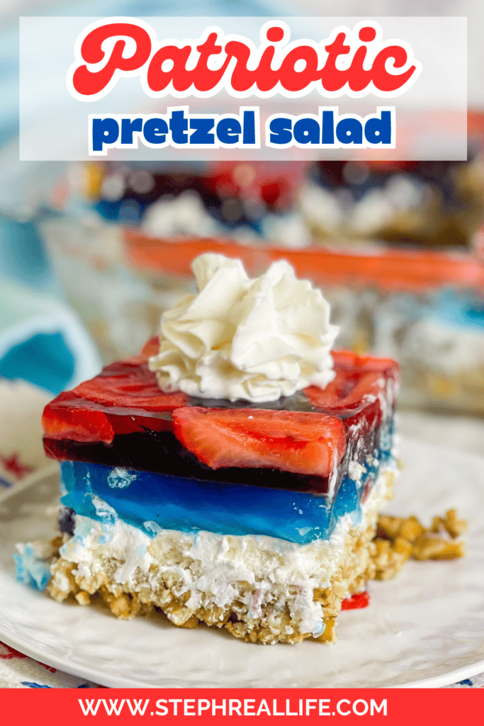 A slice of Patriotic Pretzel Salad with a pretzel crust, white cream cheese layer, blue gelatin, and red strawberry gelatin is topped with whipped cream on a plate. The full Patriotic Pretzel Salad dish can be seen in the background.