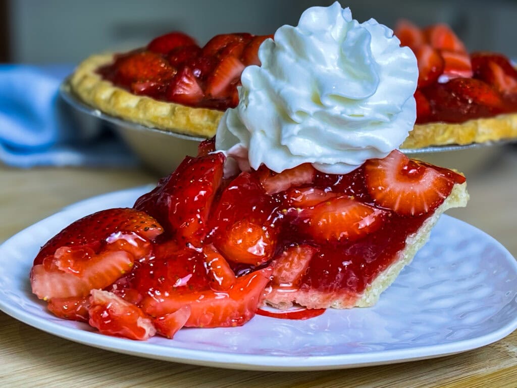 strawberry pie made with a store bought pie crust, fresh strawberries and a homemade strawberry glaze topped with whipped cream.