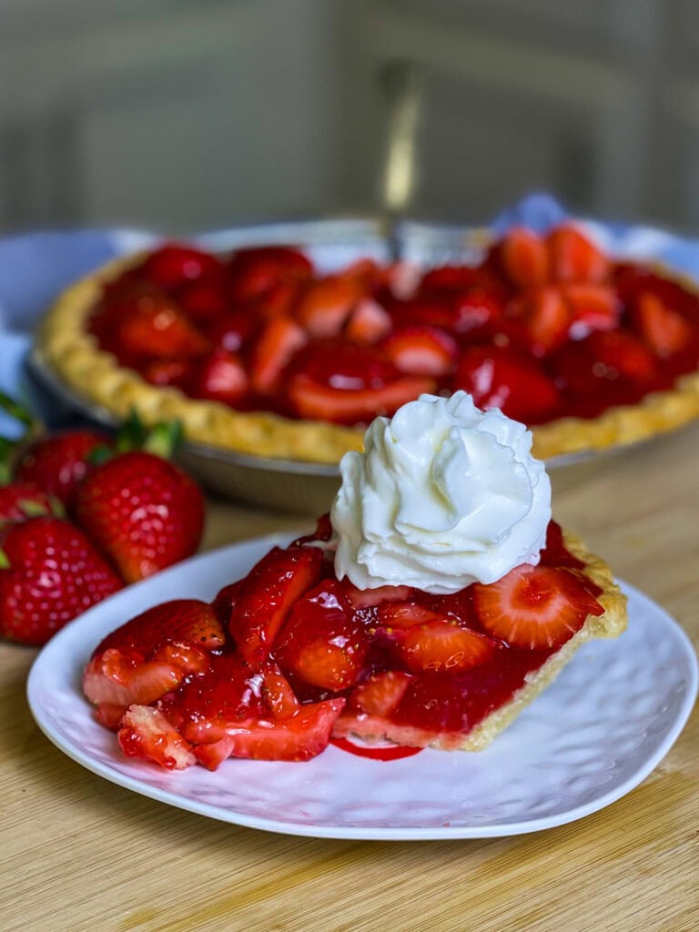 strawberry pie made with a store bought pie crust, fresh strawberries and a homemade strawberry glaze topped with whipped cream.