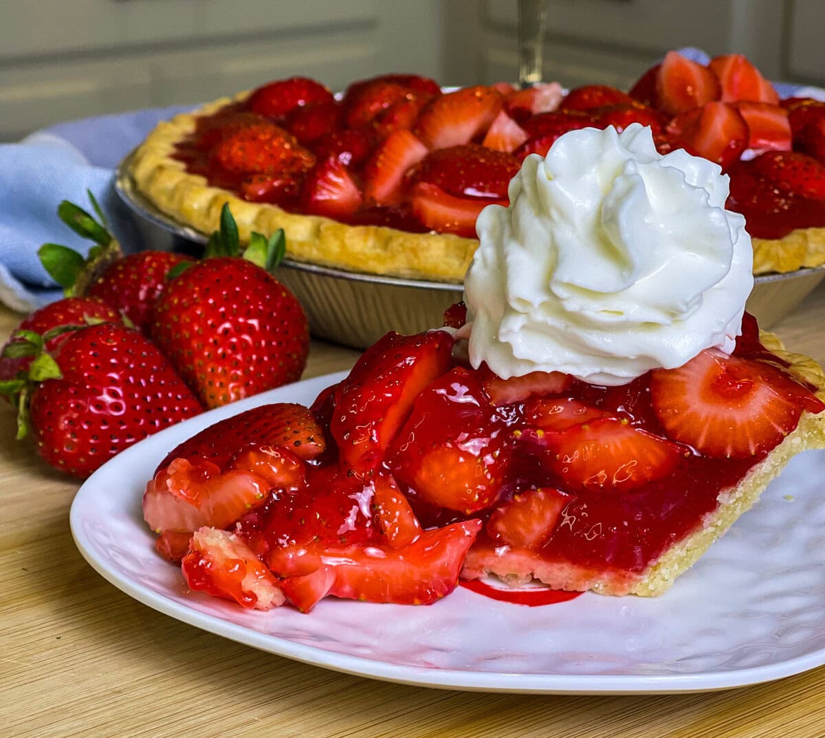strawberry pie made with a store bought pie crust, fresh strawberries and a homemade strawberry glaze topped with whipped cream.