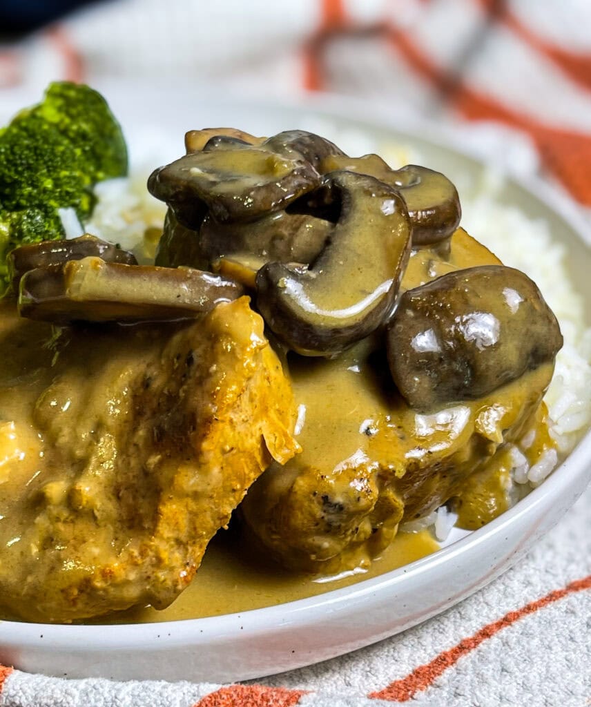 Slow Cooker Mushroom Pork Chops served on a plate with creamy mushroom gravy spooned over top, alongside mashed potatoes and green beans.