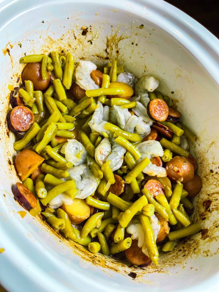 Close-up of shrimp and sausage in the slow cooker with seasoned potatoes.