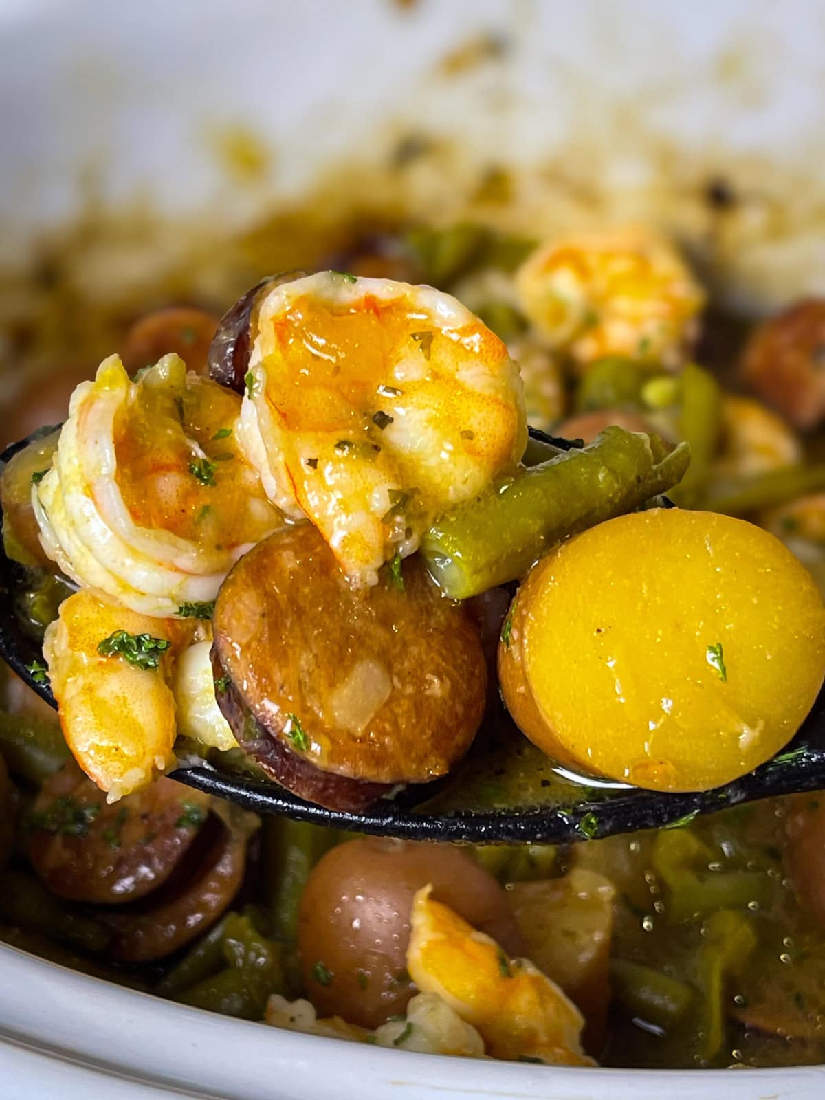 Close-up of shrimp and sausage in the slow cooker with seasoned potatoes.