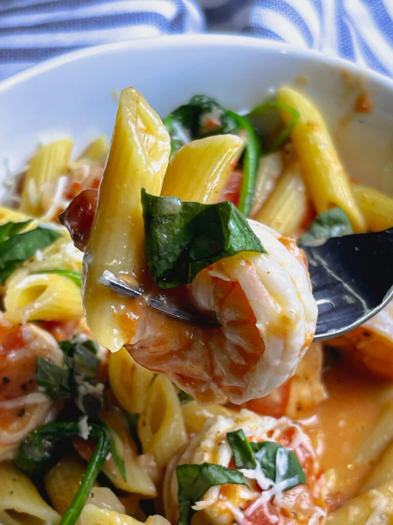 creamy one pot shrimp pasta in a white bowl, topped with fresh basil and Parmesan cheese