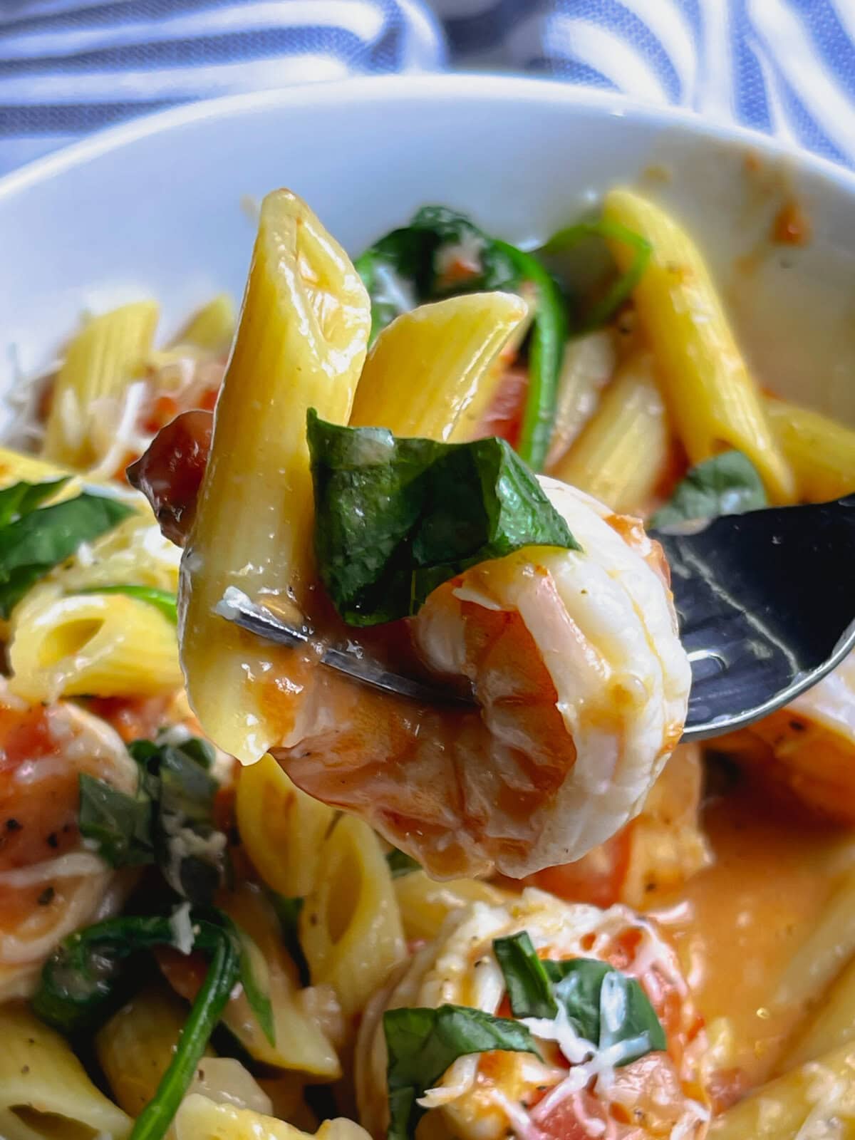 creamy one pot shrimp pasta in a white bowl, topped with fresh basil and Parmesan cheese