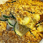 zucchini and yellow squash in a cheesy casserole with a Ritz cracker crumb topping in a 9x13 white baking dish
