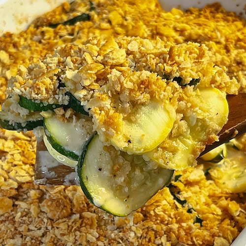 zucchini and yellow squash in a cheesy casserole with a Ritz cracker crumb topping in a 9x13 white baking dish