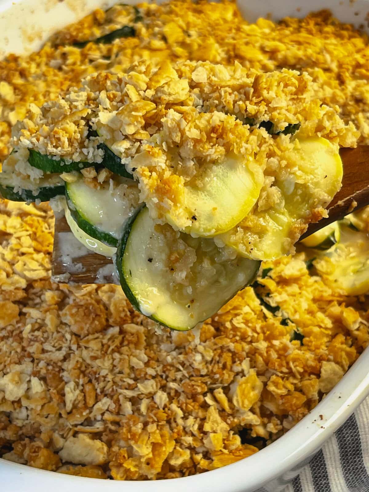 zucchini and yellow squash in a cheesy casserole with a Ritz cracker crumb topping in a 9x13 white baking dish
