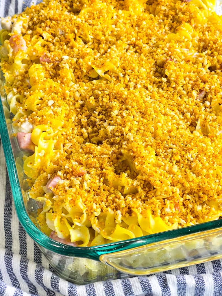 A golden-brown Chicken Cordon Bleu Casserole topped with crispy breadcrumbs and melted Swiss cheese in a white baking dish.