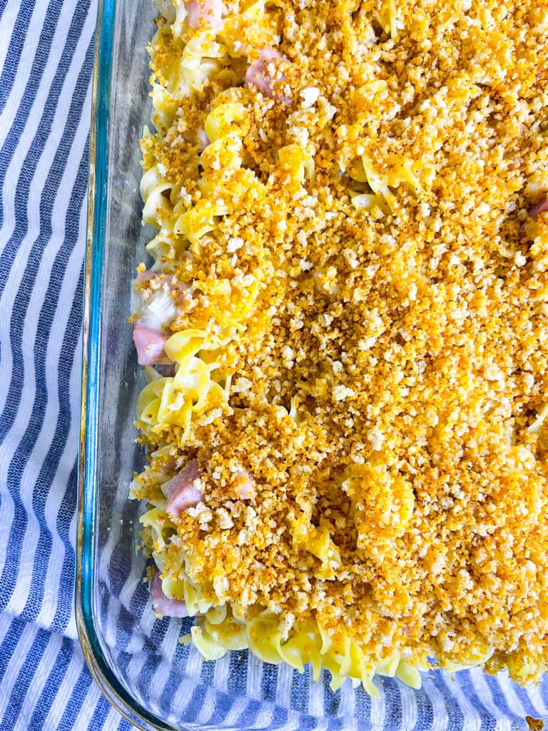 A golden-brown Chicken Cordon Bleu Casserole topped with crispy breadcrumbs and melted Swiss cheese in a white baking dish.