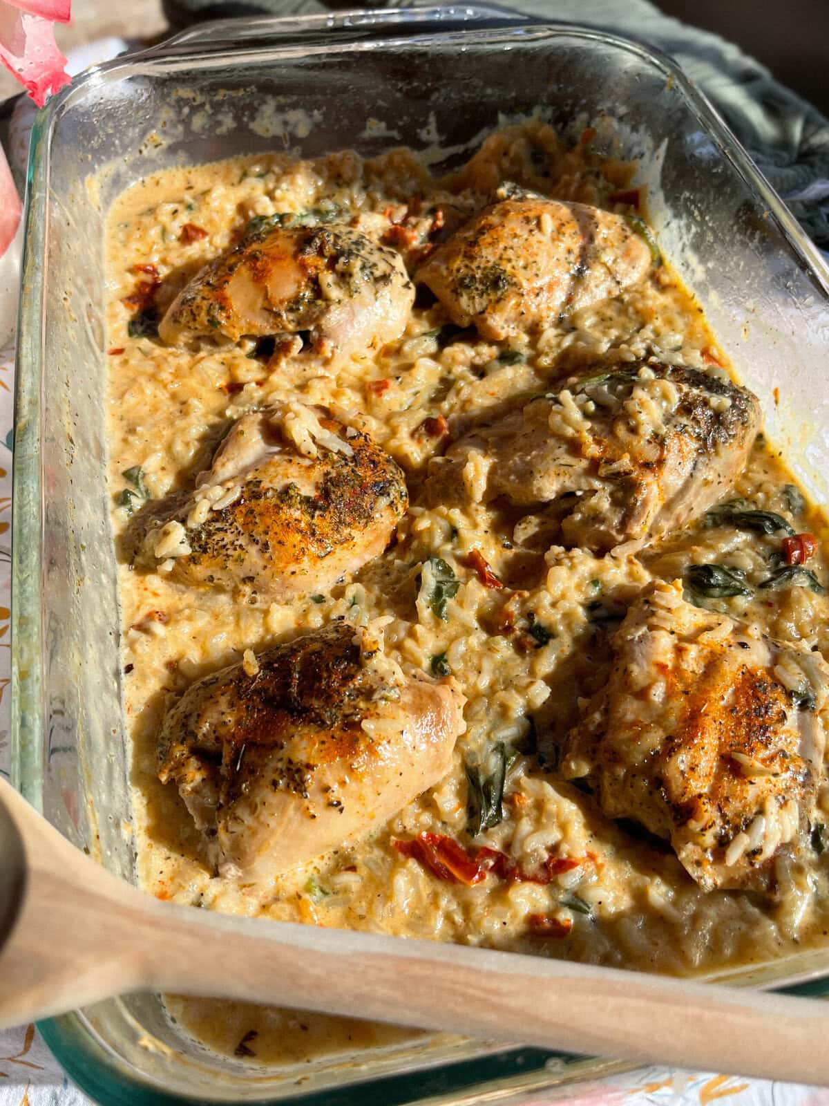 seasoned chicken thighs nestled in creamy rice in a clear baking dish