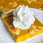 pumpkin pie made in a sheet pan topped with whipped cream