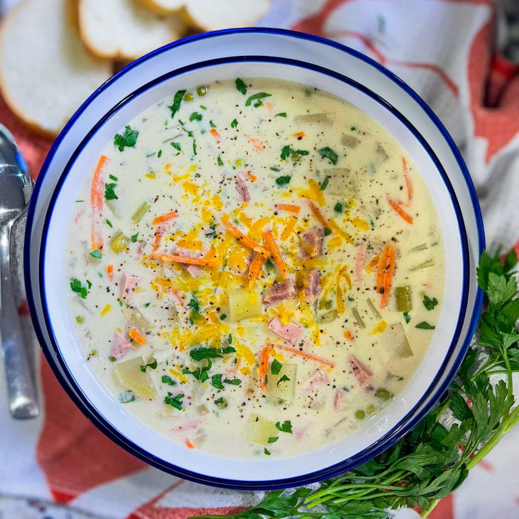 creamy soup of ham, carrots, potatoes and peas in a soup bowl