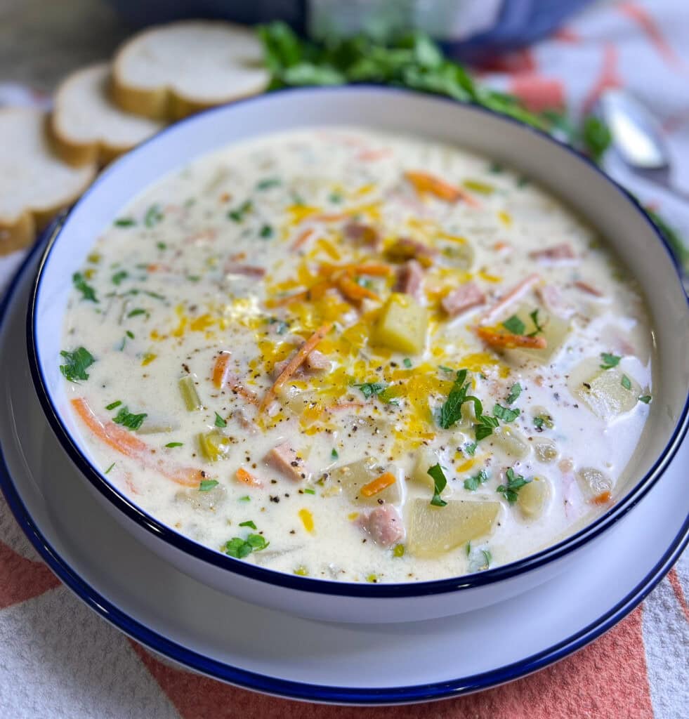 creamy soup of ham, carrots, potatoes and peas in a soup bowl