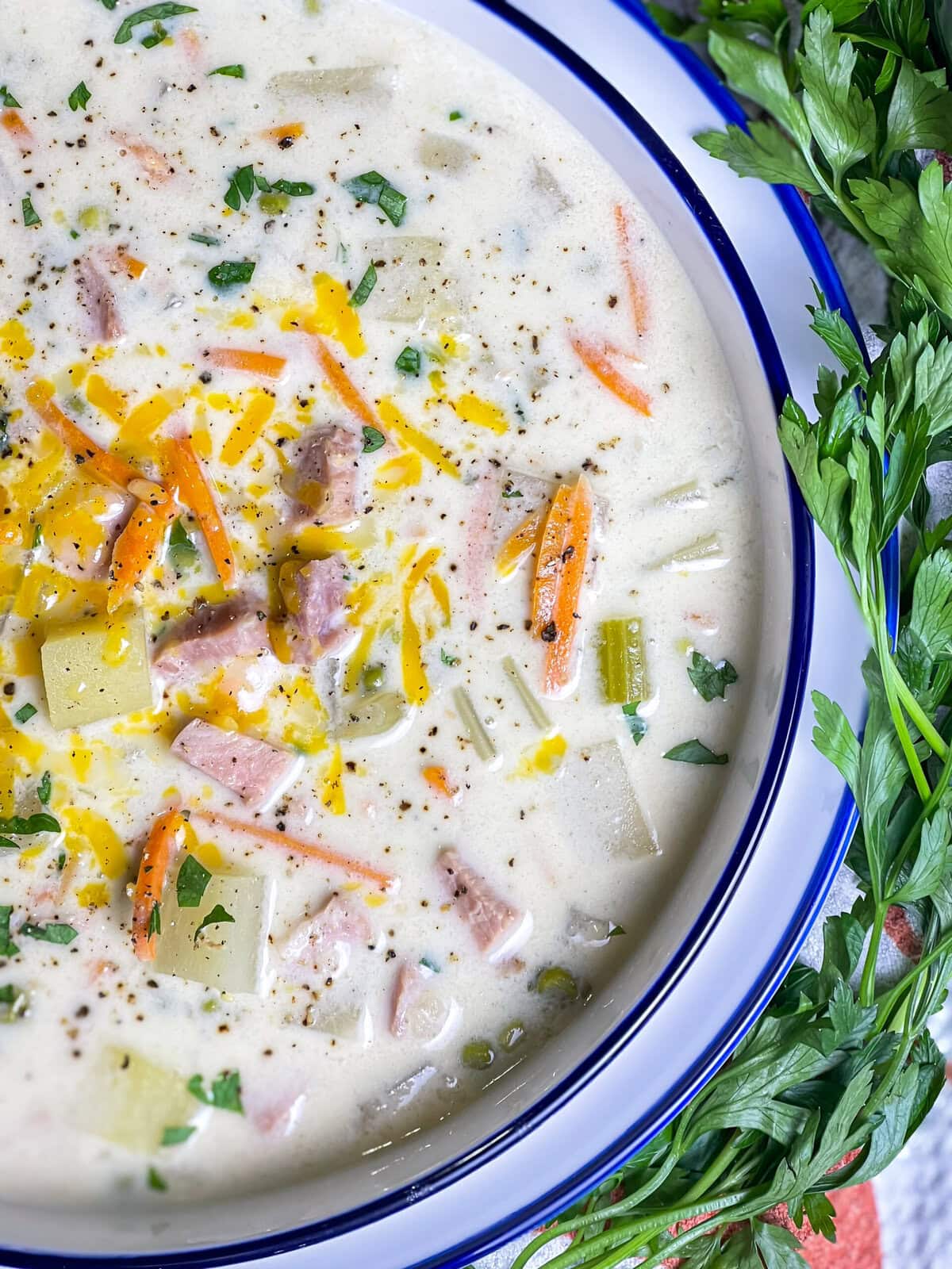 creamy soup of ham, carrots, potatoes and peas in a soup bowl
