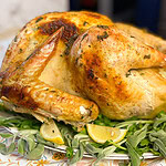 a whole roasted turkey with fresh herbs underneath on a serving platter