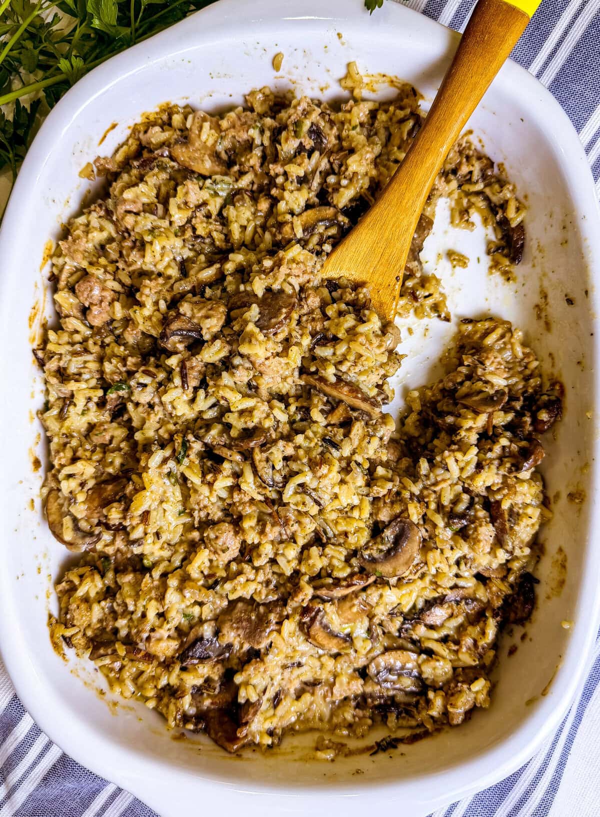 wild rice casserole with Italian sausage and mushrooms on a spoon over a baking dish