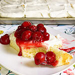 Prepared white cake mix with a white cream cheese frosting topped with cherry pie filling