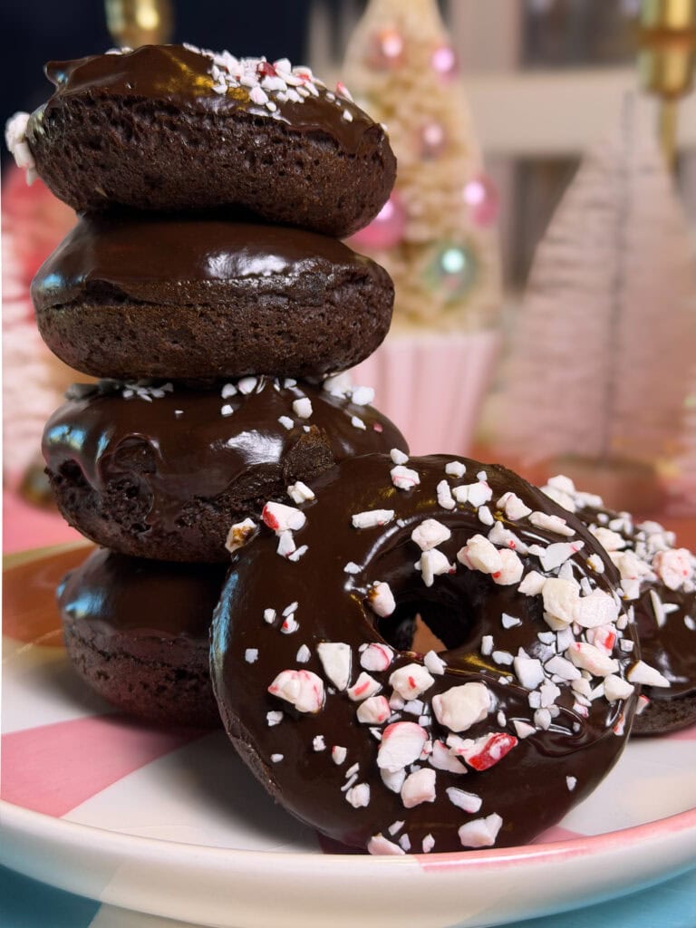Close-up of baked chocolate peppermint donuts with smooth chocolate ganache and festive crushed candy cane pieces.