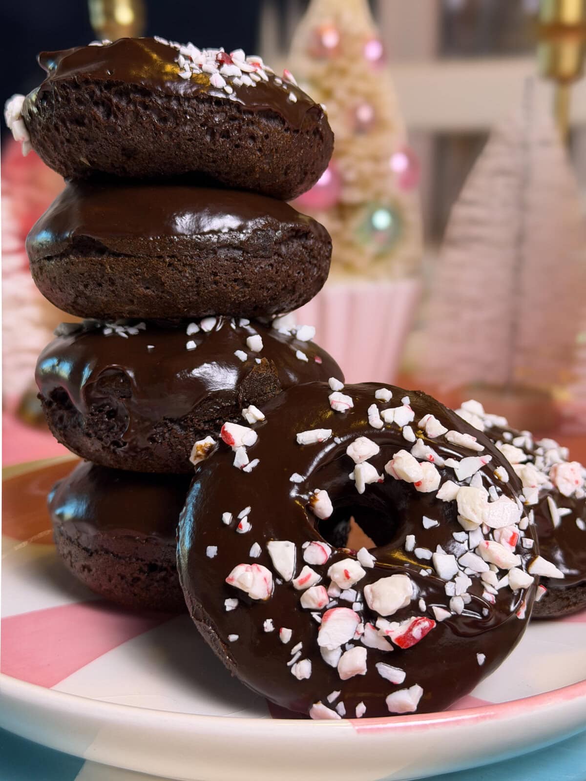 Close-up of baked chocolate peppermint donuts with smooth chocolate ganache and festive crushed candy cane pieces.