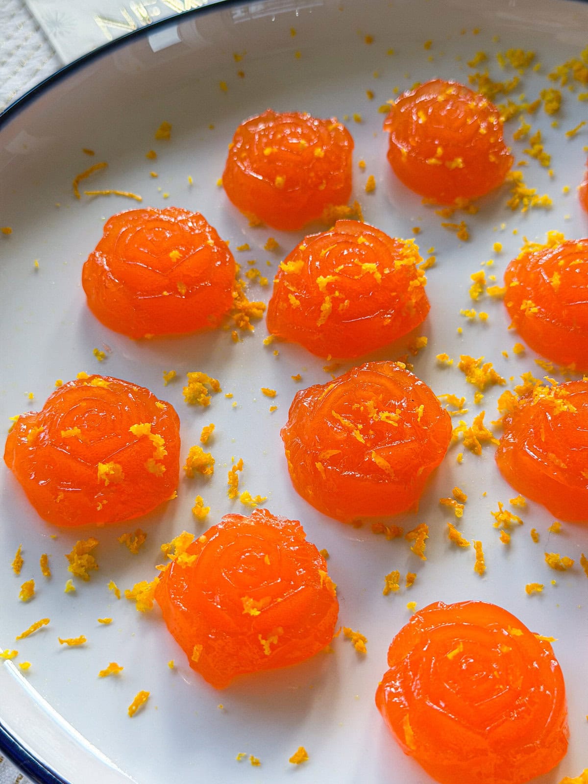 Aperol spritz Jell-O shots garnished with orange zest on a serving tray.