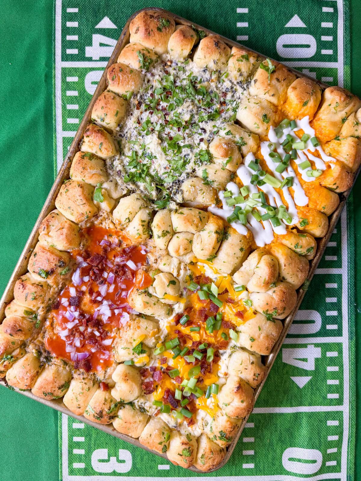 Pull-apart garlic butter pizza dough balls baked on a sheet pan surrounding four different hot dips including spinach artichoke, buffalo chicken, smokehouse burnt ends, and bacon ranch cheddar, perfect for a Super Bowl party appetizer.