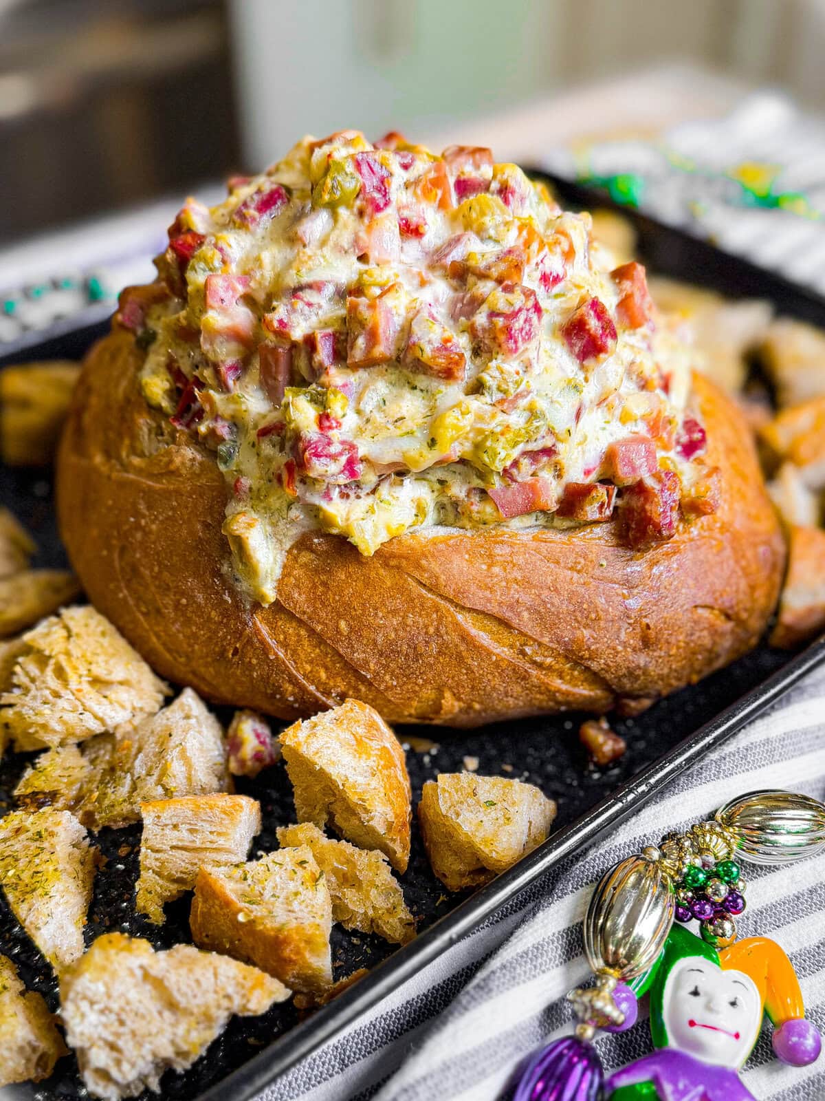 Muffaletta dip baked in a crusty bread bowl with olive salad and Italian meats