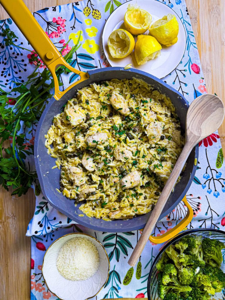creamy chicken piccata with orzo being served from a yellow skillet