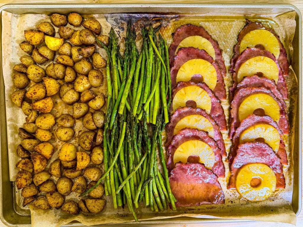Easter sheet pan dinner featuring pineapple glazed ham, golden roasted potatoes, and tender asparagus cooked together on one pan.