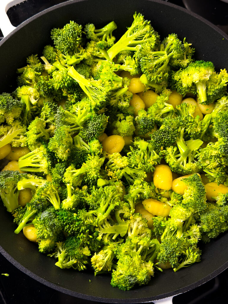 Broccoli florets and yellow beans sautéing in a black frying pan, creating a vibrant and colorful vegetable dish.