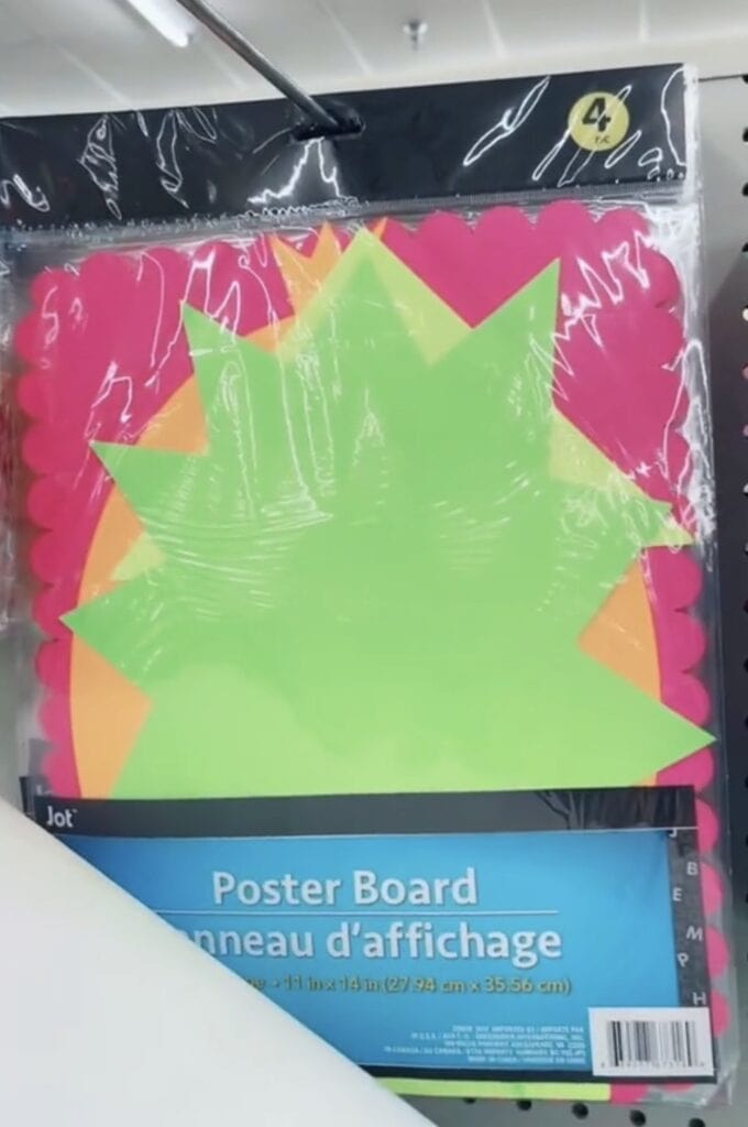 A package of colorful starburst-shaped poster boards in neon green, orange, and pink, hanging on a store display rack. The packaging is labeled Poster Board in English and French.