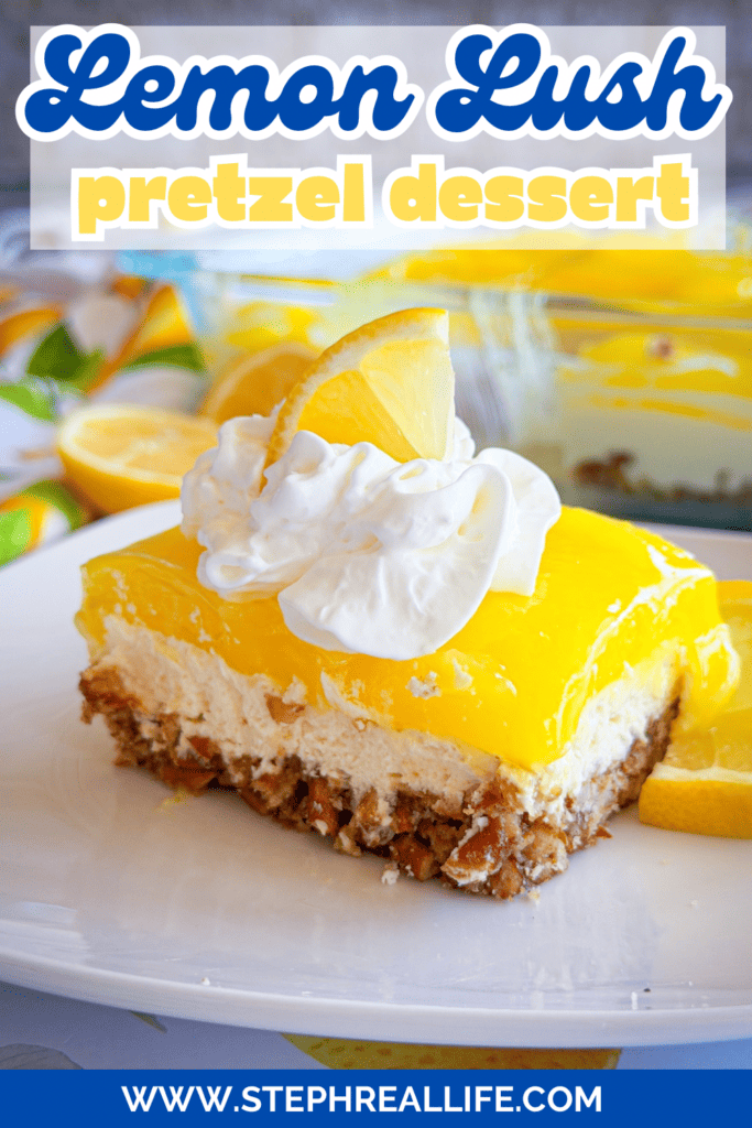 A slice of lemon lush pretzel dessert topped with whipped cream and a lemon slice sits on a plate. The dessert has layered pretzel crust, creamy filling, and lemon topping. The background shows more dessert and lemon wedges.