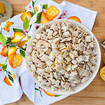 A bowl of powdered cereal snack sits on a wooden surface, surrounded by lemon halves, a grater, a citrus-themed towel, and a citrus juicer.