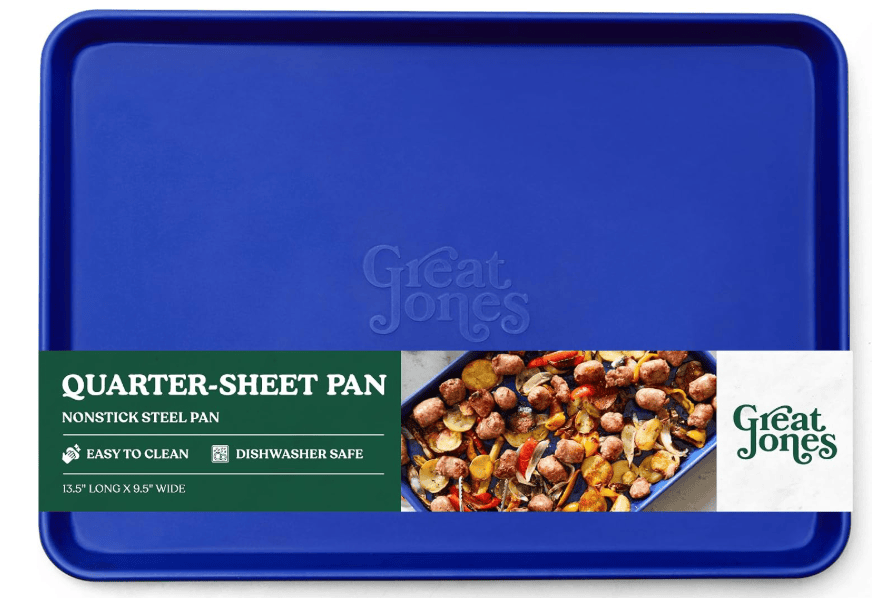 A blue quarter-sheet pan by Great Jones, labeled as nonstick steel, easy to clean, dishwasher safe, 13.5 x 9.5, with an image of cooked meatballs and vegetables on the packaging.