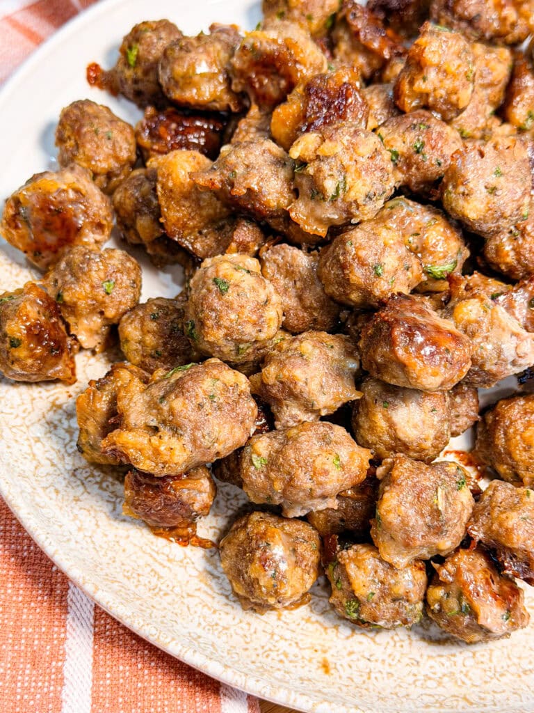 A pile of small, browned meatballs with visible flecks of herbs on a patterned plate.