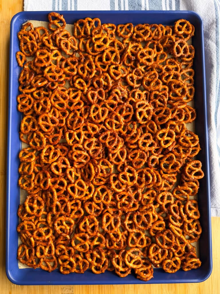 A blue baking sheet filled with a dense layer of small, golden-brown salted pretzels.
