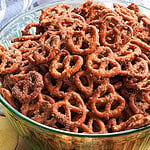 A large glass bowl filled with cinnamon sugar pretzels, surrounded by apple slices and cinnamon sticks.