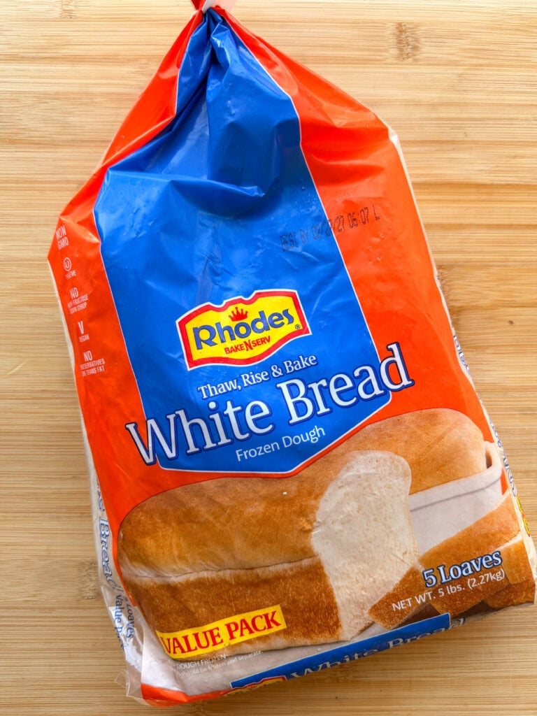 A plastic bag of Rhodes Bake-N-Serv frozen white bread dough containing five loaves.