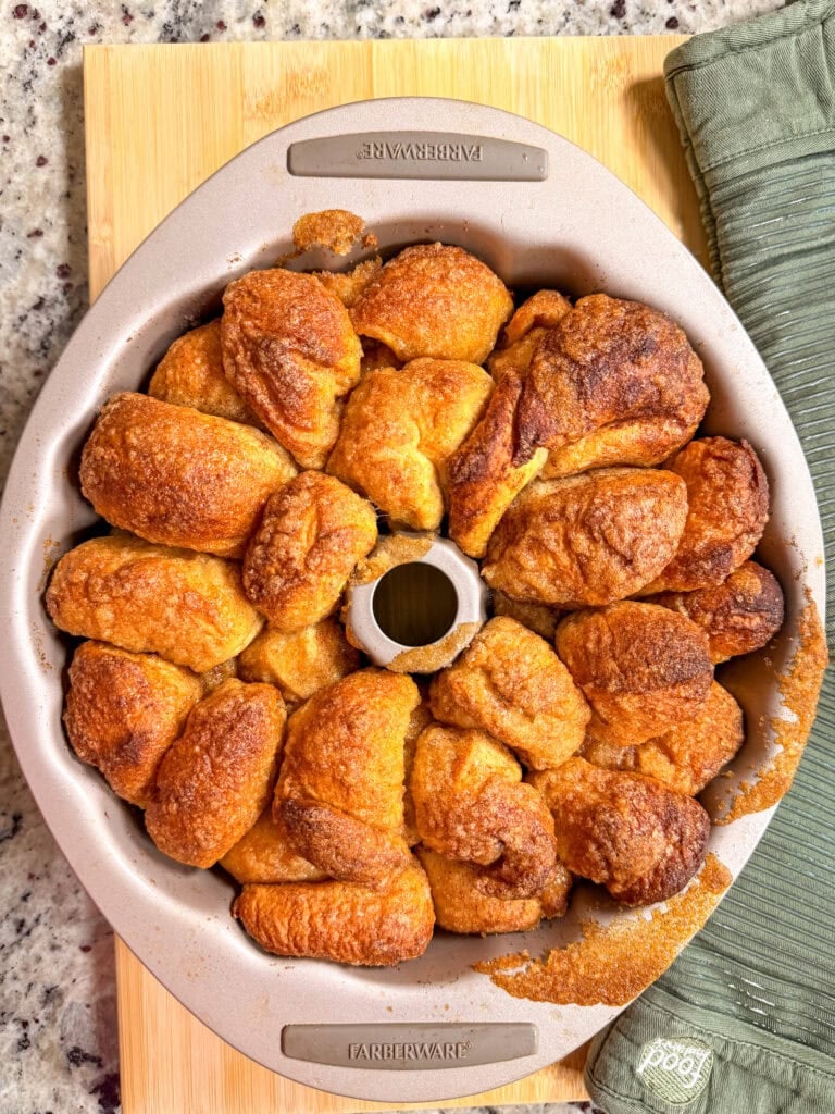 Golden-brown monkey bread baked in a round Farberware fluted pan on a wooden cutting board.