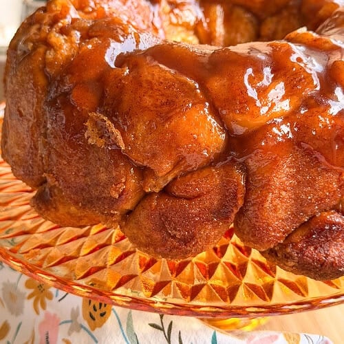 A glazed monkey bread ring on a glass cake stand.