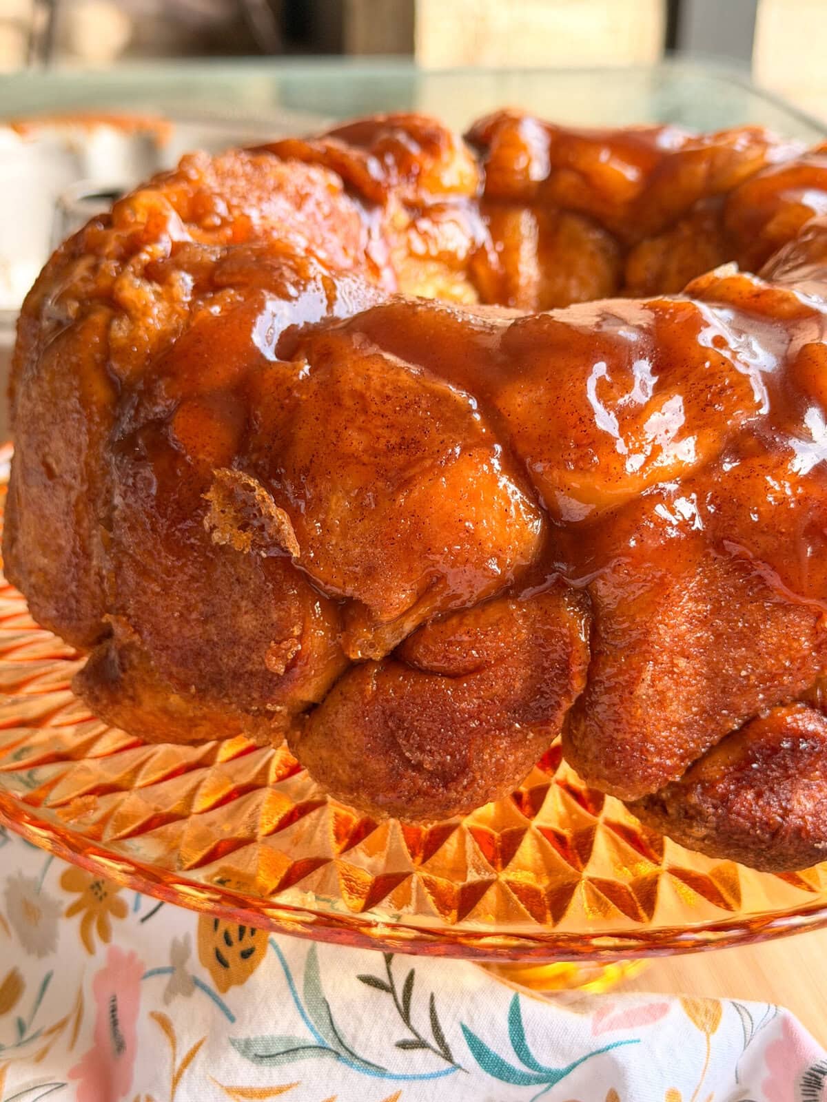 A glazed monkey bread ring on a glass cake stand.