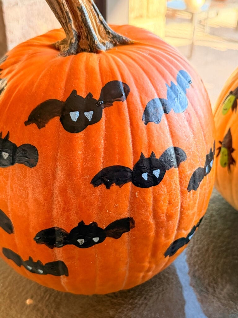 Orange pumpkin decorated with hand-painted black bats with white eyes.